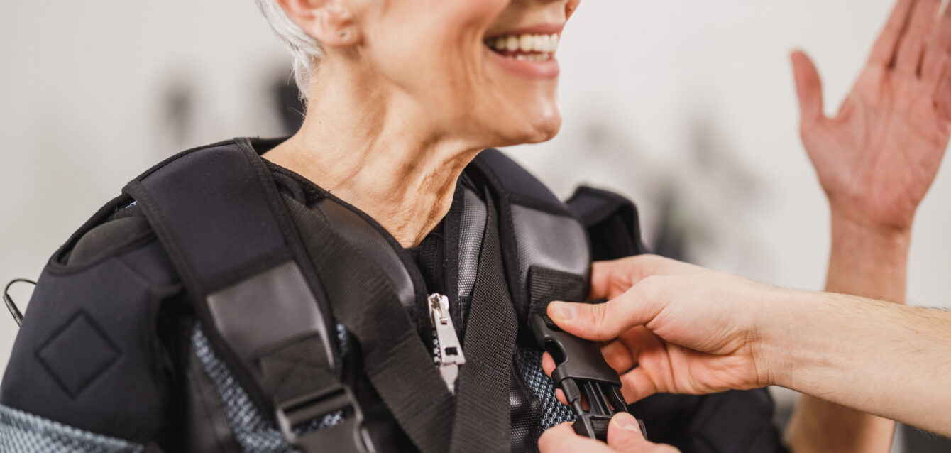 Fitness Instructor Putting An Ems Suit To A Woman